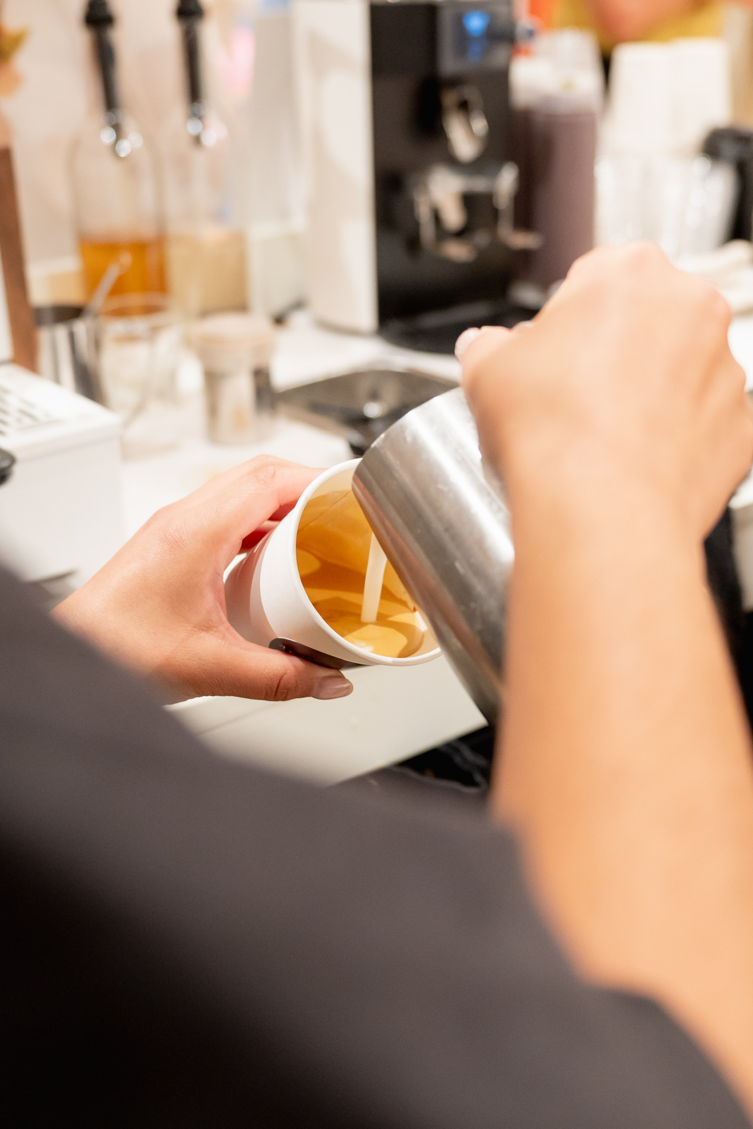 Guests learning latte art with an Anech&oacute; barista pouring steamed milk into a cup